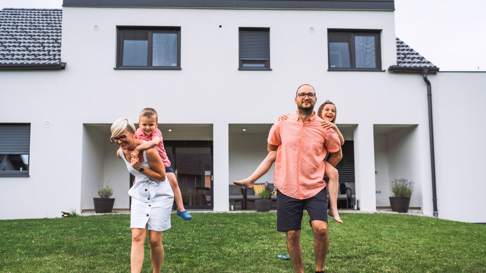 Família feliz em frente à casa própria conquistada com consórcio Porto Seguro